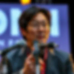 Hideo Kojima speaking at a press event, discussing his departure from Sony, with a focused expression and microphones in front of him.