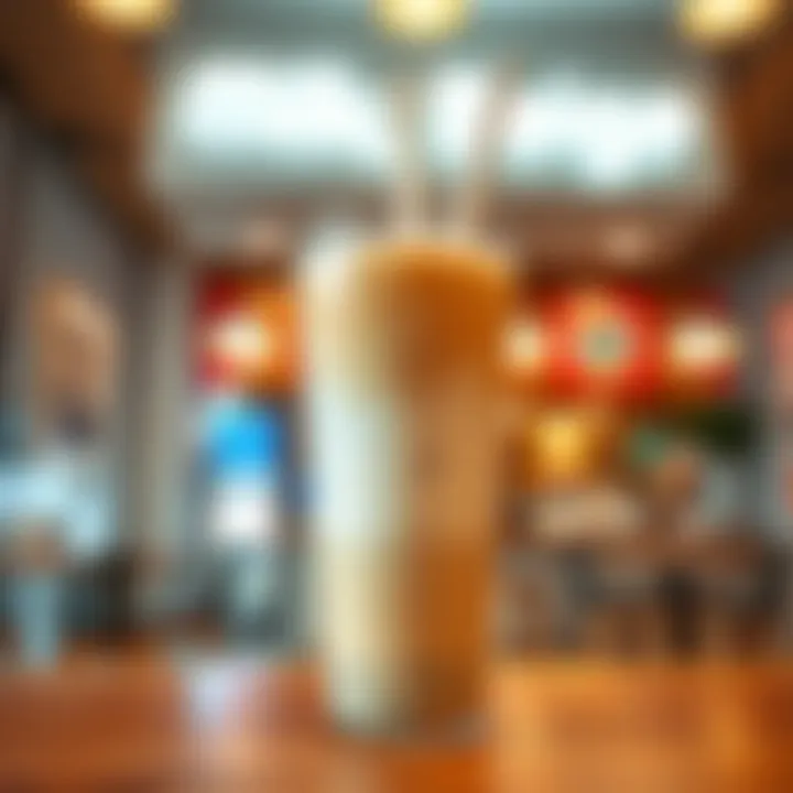 A creamy Milk Tea Beige drink in a clear cup with a straw, set against a welcoming eta shop background.